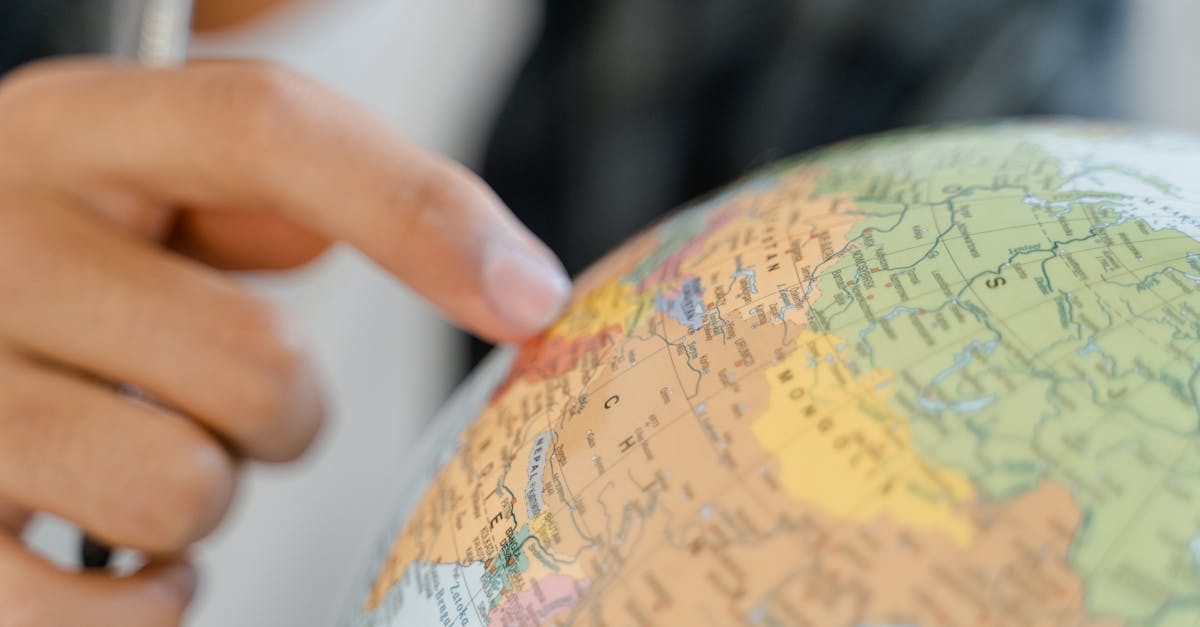 A close-up of a hand pointing at a globe, highlighting exploration and travel concepts.