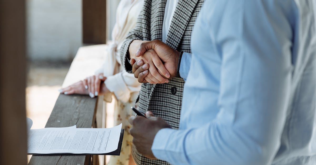 A close-up of hands shaking over a signed property agreement, symbolizing a successful real estate deal.