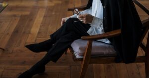 A woman holding glasses, seated indoors, exuding professionalism and calm.