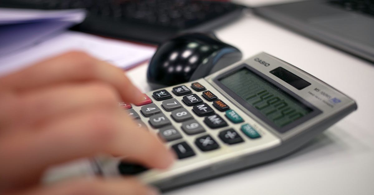 Close-up of a hand using a calculator on an office desk for accurate calculations.