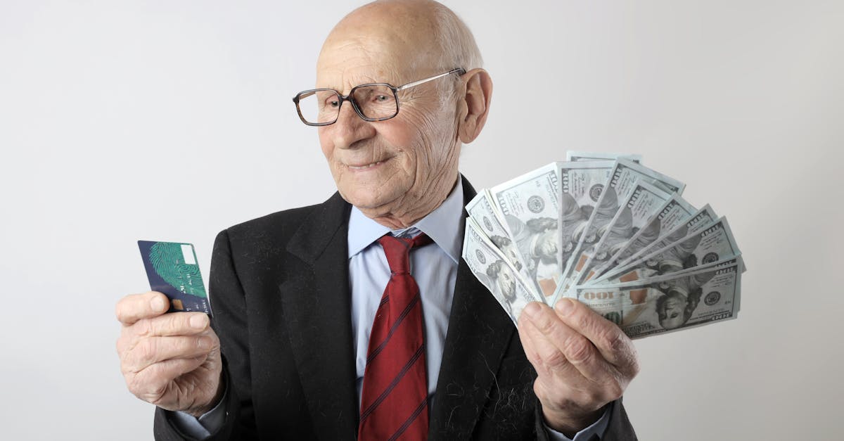 Elderly man in a suit holding a credit card and US dollar bills, representing finance and wealth.