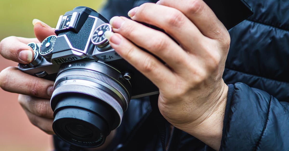 Hands holding a camera in an outdoor setting, showcasing a professional photographer’s gear.