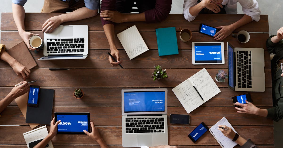 Overhead view of a diverse team in a business meeting using laptops and tablets.